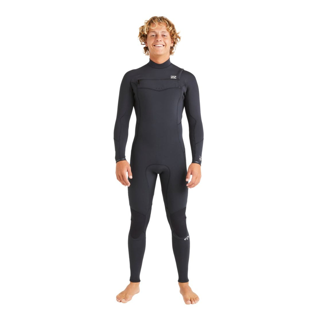 A man standing in a black long sleeve Billabong Absolute Natural 3/2mm mens wetsuit with a chest zip entry system. 