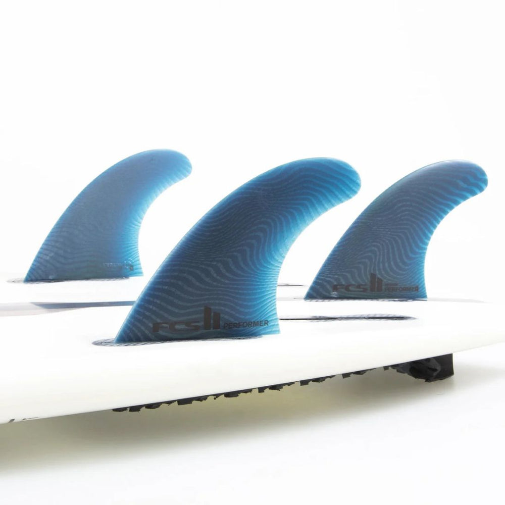 Close-up of a surfboard with three blue fins on a white background